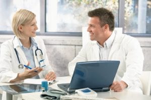 two happy doctors with clipboard and computer